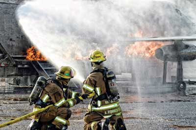 (16) VBFD firefighters performing suppression activities on a gas-fueled jet simulator in December 2011. [Photo by Kirk Kellerhals, Virginia Beach (VA) Fire Department.]