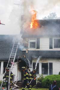 (5) Fire has traveled from the initial fire area in the rear up the exterior and into voids; the fire is now showing out of the vent hole, and the attic area appears to be well involved.