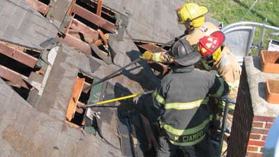 (4) Two firefighters work in unison to remove the decking and open the roof from the safety of the tower ladder bucket.