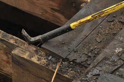 (5) The hook's tip is placed on the top of the joist, and the remaining portion of the head is placed under the roof sheathing. Then the hook's handle is lifted vertically, and the tip acts as a fulcrum to pry the sheathing off. (Photo by J.J. Cassetta.)