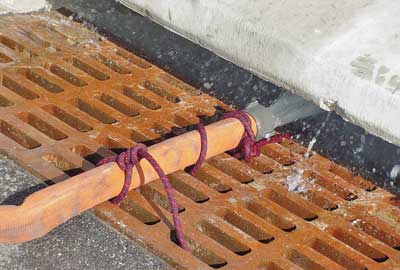 (12) A hose lashed to a storm sewer grating flows water to keep the pump cool.