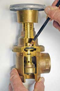 (19) The valve's hand wheel and threaded stem indicate that the valve is open, but it is actually closed because there is no water flowing. Water pressure downstream of the valve, represented by the pencil, exerts a downward force on the piston, closing the floating valve. This photo explains why PRVs cannot be back fed as inlets if an FDC fails.