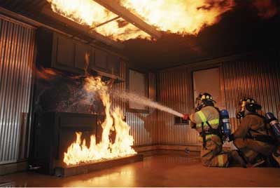 (5) This realistic burn room depicts a kitchen fire. Firefighters are practicing proper stream management techniques. (Photo courtesy of Draeger Safety, Inc.)