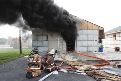 (5) A knockdown/rekindle time test facility. To simulate probable firefighting tactics, flow was initiated down a hallway leading to a fully enveloped room (simulating attempts to cool a gas layer), halted for 15 seconds (simulating a firefighter moving down a hall), then was recommenced into the burning room. (Photo by C.A. Dicus.)