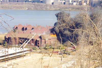 (1) This is in 2000. You can see the smoke is going toward the D exposure. Note the fire has broken through the roof. Also notice that no master streams are pushing the fire back into the building. The water tower is knocking down the combustible wall and roof fire. Although it doesn't look it, things are getting better. (Photo by Robert Scollan.)