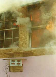 (11) Heavy fire inside the test facility melts and burns the energy-efficient, double-pane vinyl frame and sash window (on the right) before the wooden-frame, single-pane window (on the left). (Photo by author.)