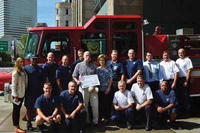 (1) (Center): William H. Newland and Tricia Newland, RPFFCF secretary of the Fire Fighters Cancer Fund; (far left) Kathleen Sullivan, assistant director of development at Dana-Farber; and on-duty personnel of Boston Fire Department's Rescue 1, Engine 10, and Ladder 3. 