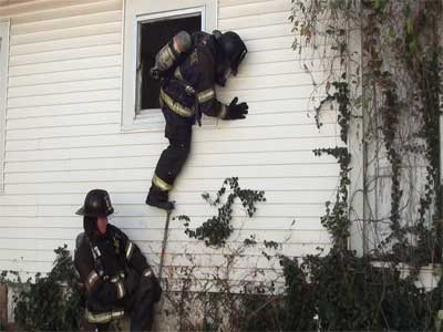 Drive the pike of the halligan into the wall to create a secondary step when using another firefighter's knee as the first step.