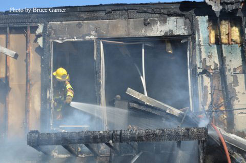 A firefighter applies water to the fire site.