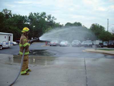 firefighter is demonstrating the use of a low-pressure medium fog stream