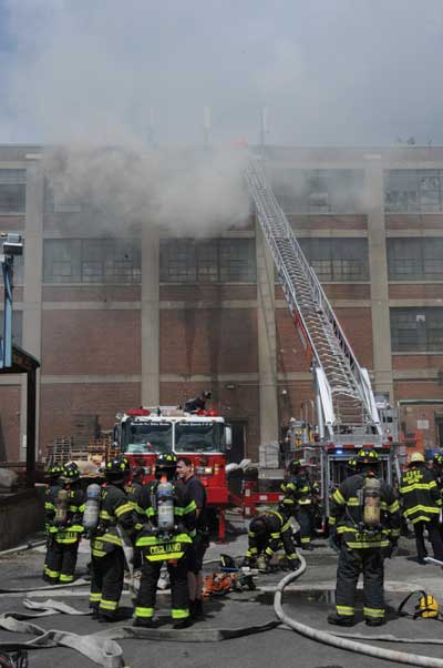 (3) The tower ladder is being set up, and the aerial most likely should be moved away from the smoke so members on the roof have a way off the roof away from the operating tower ladder.