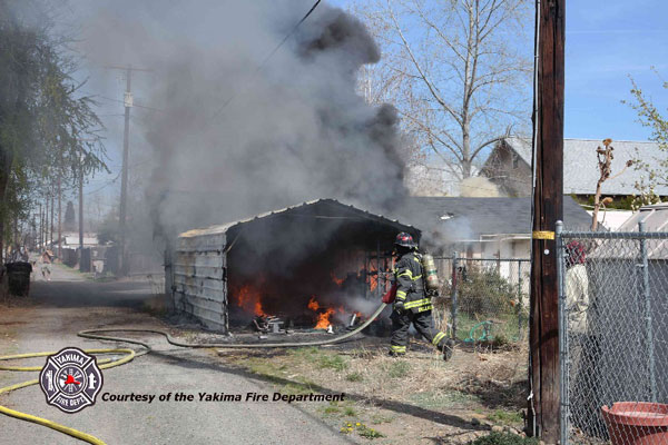 Firefighter moving a hoseline at a fire in an alley.