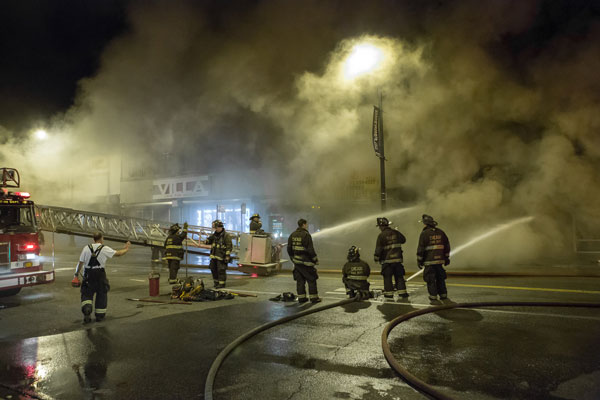 Firefighters operate hoselines at a fire scene.