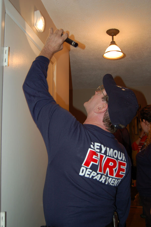 A Seymour firefighter examines a resident's smoke alarm setup.