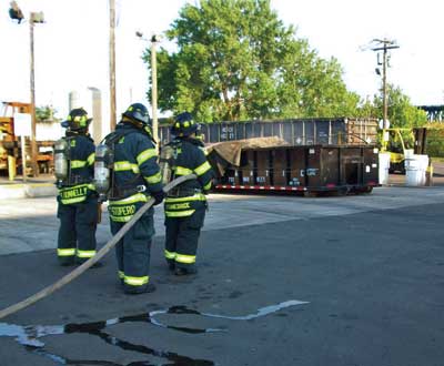 (1) Firefighters keep their distance at a smoldering dumpster fire.Photo by Joseph Viscuso.