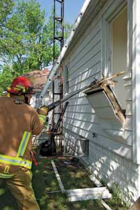 (2) Two firefighters use hooks to remove the cut section of wall.