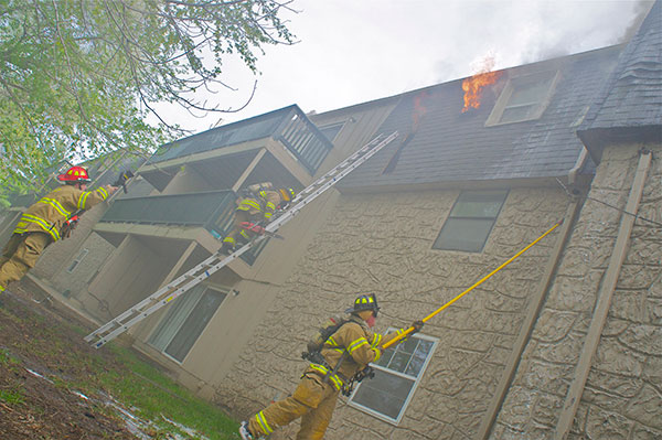 An exterior view of the second fire, as flames vent from the mansard roof of the apartment building.