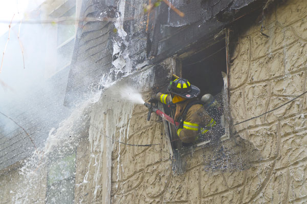 A firefighter trains a hose stream on fire in the second response.