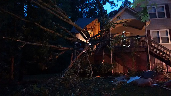 A tree rests on a house during an emergency incident.