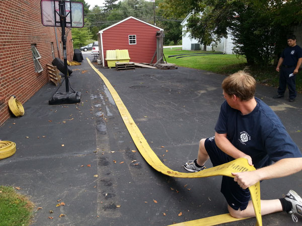 Firefighters perform a hose pull as part of a functional fitness exercise.