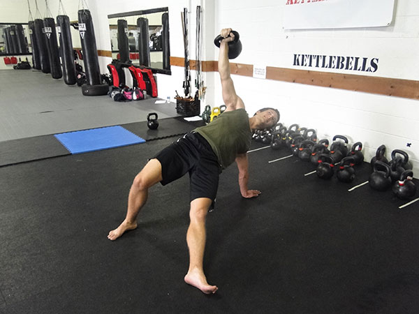 Performing a Turkish Getup with a kettlebell.