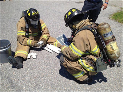 A firefighter attempts to assemble PVC pieces used in the drill after successfully navigating the course.