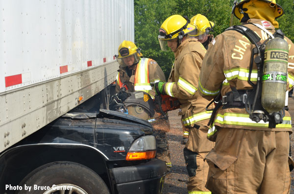 Chattanooga (TN) firefighters use a saw at an incident in which a pickup truck became wedged underneath an 18-wheeler.