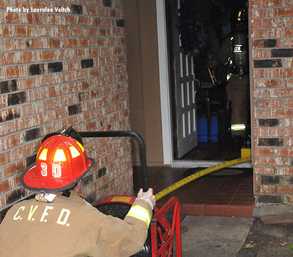 Community Volunteer Fire Department member operates a ventilation fan at the door of a fire scene.