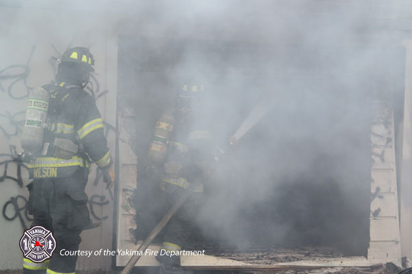 Firefighters operate a hoseline in smoky conditions.