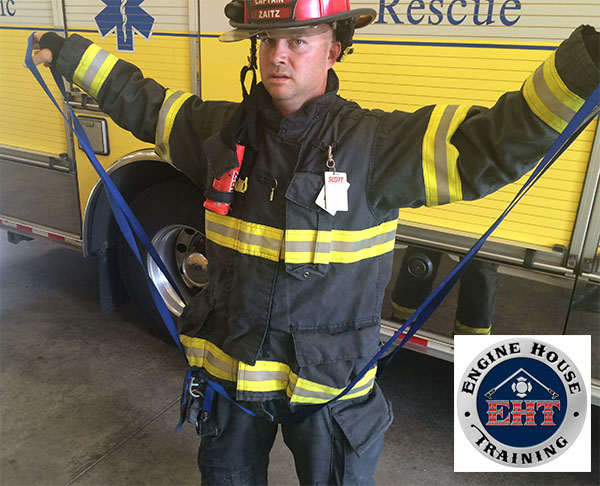 A firefighter demonstrates establishing a hasty harness using webbing.