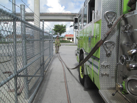 The backup firefighter stretches toward the front of the apparatus until the hose has cleared the bed.