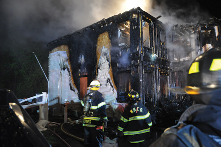 (2) This modern house had extensive and rapid fire envelopment outside because of the combustible siding, insulation, and sheathing. Note the collapse of the truss roof, which occurred early in the fire.