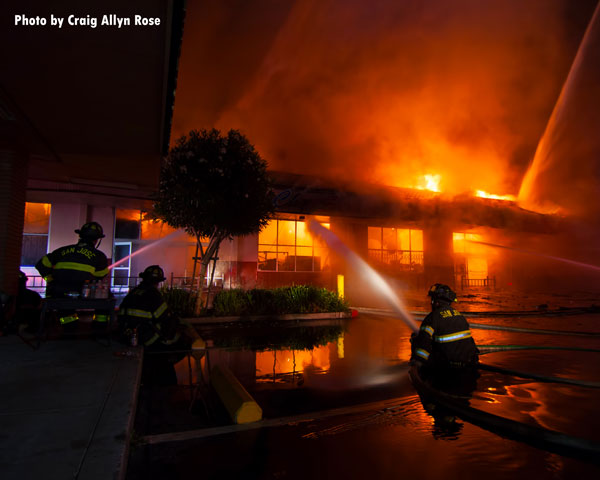 Firefighters train various hosestreams on the burning building.