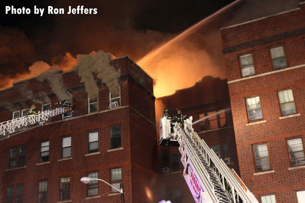 Firefighters in aerial devices battle huge flames at a 5-story apartment building in Passaic, New Jersey.