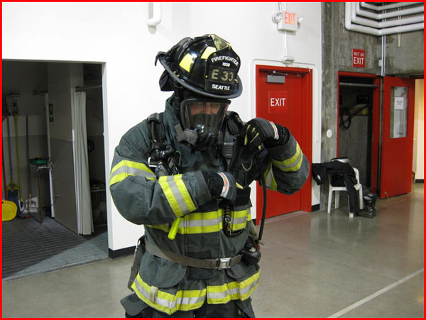 A firefighter wearing his turnout gear accessing his radio