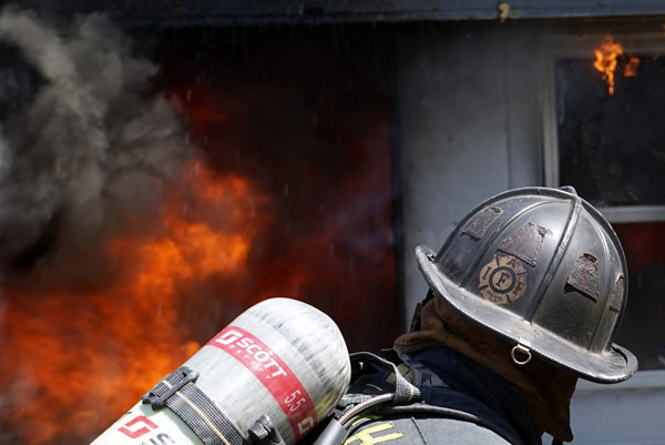 A firefighter confronts a heavy volume of fire.