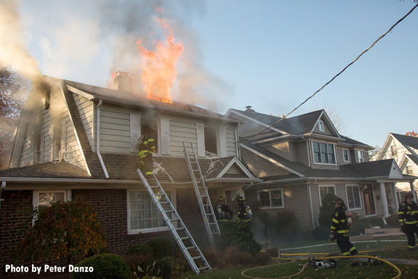 Fire vents through a hole in the roof as firefighters work at a house fire in River Edge, New Jersey.