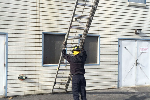 A firefighter raises a ladder during a training drill.