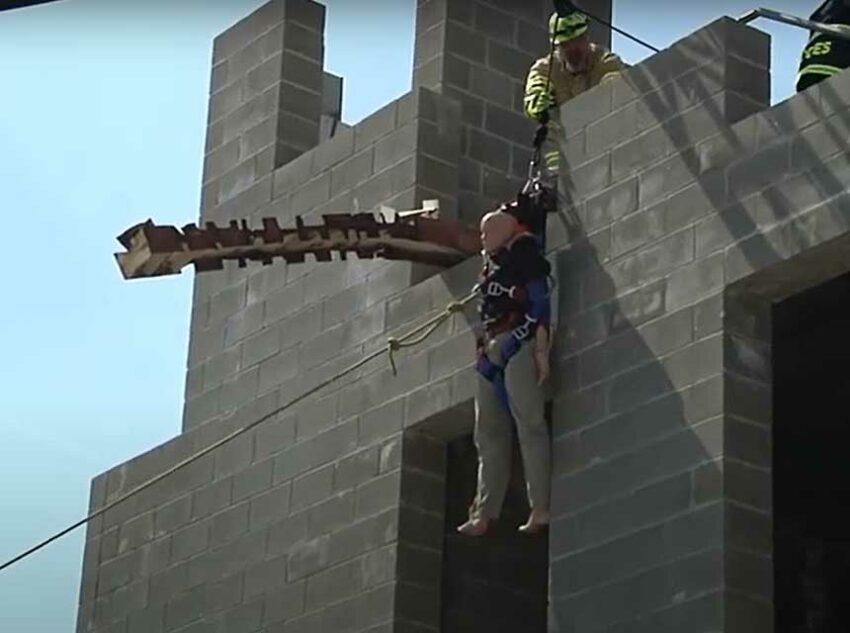 Firefighters use an aerial ladder to lower a victim with ropes