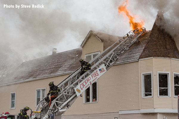 Firefighters on a Cicero aerial ladder at a house fire.