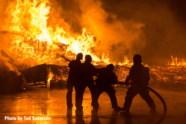 Firefighters use a hoseline on flames during a fire at a pallet yard in Fontana, California.