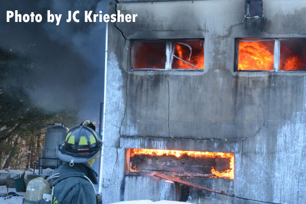 Fire tears through a wax factory in Tuscarora, PA with a Mahanoy City firefighter in the foreground.