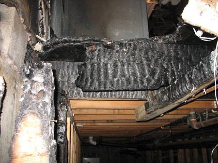 (5) A view of the hole as seen from the basement, looking up into the fire area. Note the heavy charring and damage to the two- × six-inch joist.