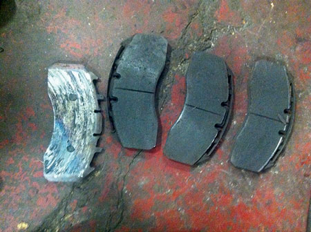 (14) Three of the four disc brake pads shown are worn, but the one on the left has completely lost its lining and was stopping the vehicle with “metal on metal.” 