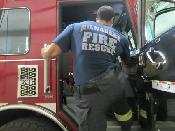 A firefighter performs a hip hike movement to board the apparatus.