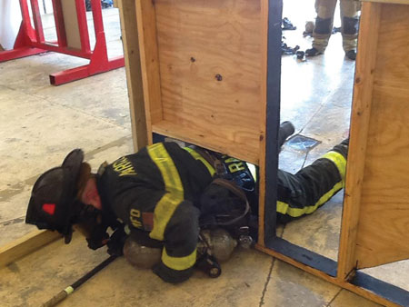 (3) Position, arrange, and remove. The purpose of this drill is for the firefighter to learn how to maneuver the body through a reduced profile while on SCBA air. <i>(Photo courtesy of Robert Ramirez.)</i><b>