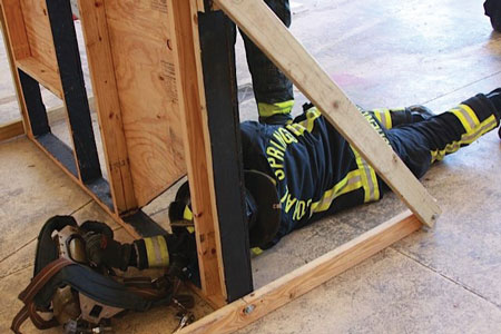 <b> (4) </b>Position, arrange, and remove. As in photo 3, the firefighter is tasked with moving his body through a reduced profile while on air. <i>(Photo courtesy of Robert Ramirez.)</i>