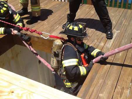 (7) The preconnected high-rise attack line is used to simulate the lowering of a rescuer into a hole through which another firefighter fell during the Nance Drill. <i>(Photo courtesy of Mark Rossi.)</i>