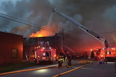 (1) Aerial devices are positioned to allow for elevated master stream delivery. The locations of overhead wires have been taken into account, and the apparatus was moved or the overhead lines were deenergized. <i>[Photos courtesy of the Indianapolis (IN) Fire Department.] </i>