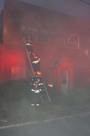 (3) A member makes his way up a portable ladder to do a quick search of the second floor for possible victims. Another member will enter the room with him, and a third member will monitor conditions and stay at the window as an emergency contact.